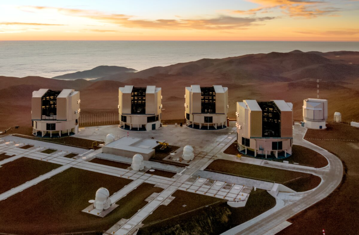 Professional telescopes of the Very Large Telescope at Paranal Observatory in Chile, silhouetted at sunset